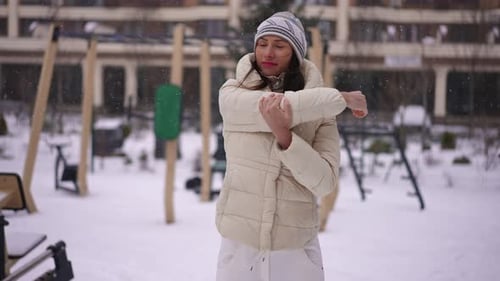 Woman Stretching Arms in Snowy Playground