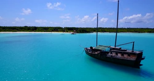Soft aerial drift over Maldives shore. Lone fishing boat lingering in crystal clear water on a sunny