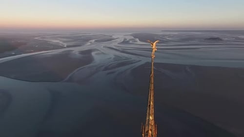 Cinematic view of Mont Saint-Michel Abbey and bay at sunset, Normandy, France. Aerial backward and s