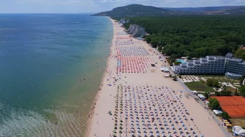Drone Video of a Sprawling Beach with Rows of Umbrellas Sunbathers and Water Activities The Aerial