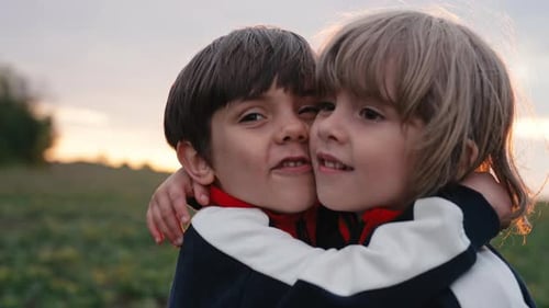 Two Happy Children Embracing Outdoors at Sunset
