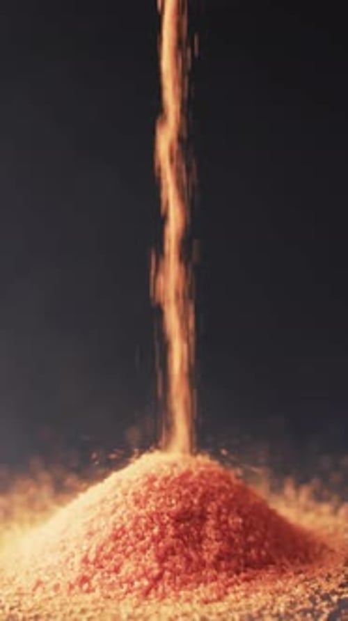 Vertical video of close up of heap of red sand grains and copy space on black background