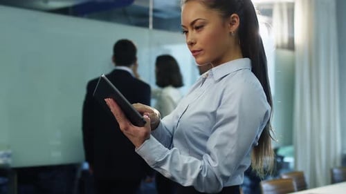 Businesswoman using Tablet in Crowded Office