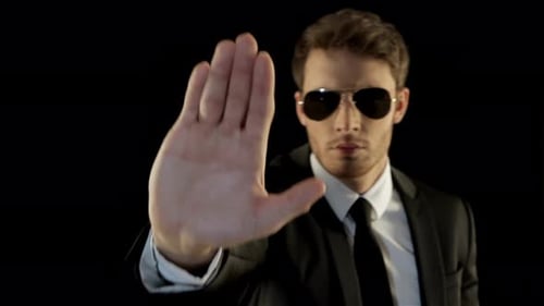 Serious Man in Suit Makes Stop Gesture
