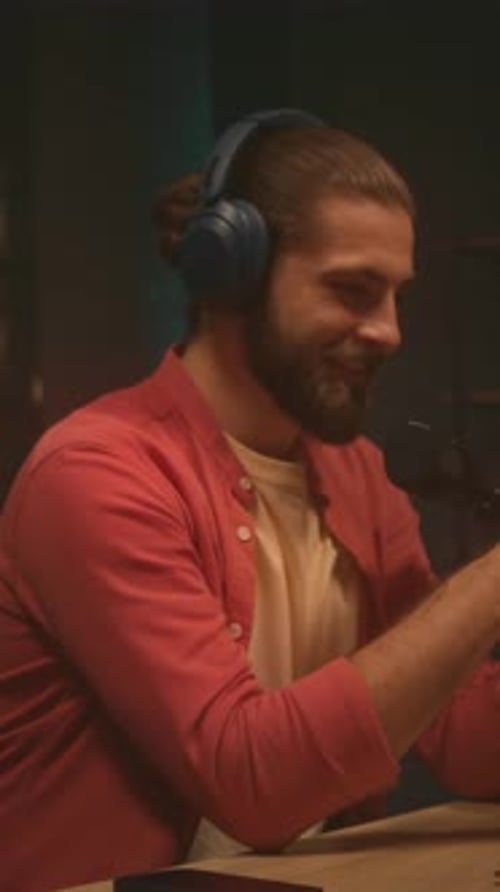 Speaker in Studio Man Using Headphones and Microphone Bearded Host Engaging Audience with Expressive
