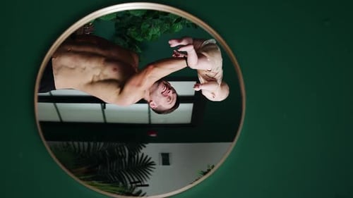 Father Holding Baby Reflected in Round Mirror