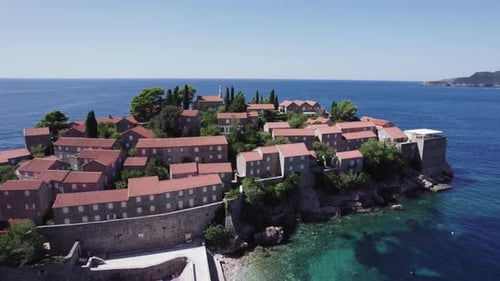 A drone flies over the island of Sveti Stefan on a sunny day in Montenegro