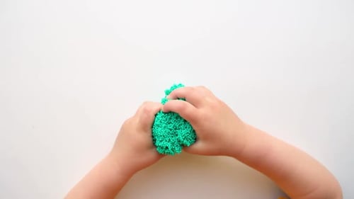 Baby Hands Playing with Textured Slime with Bubbles Stretching the Gooey Substance on White