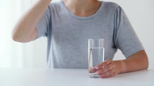 Woman Taking Pills with Glass of Water