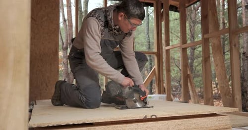 A Worker Uses a Circular Saw to Cut Plywood
