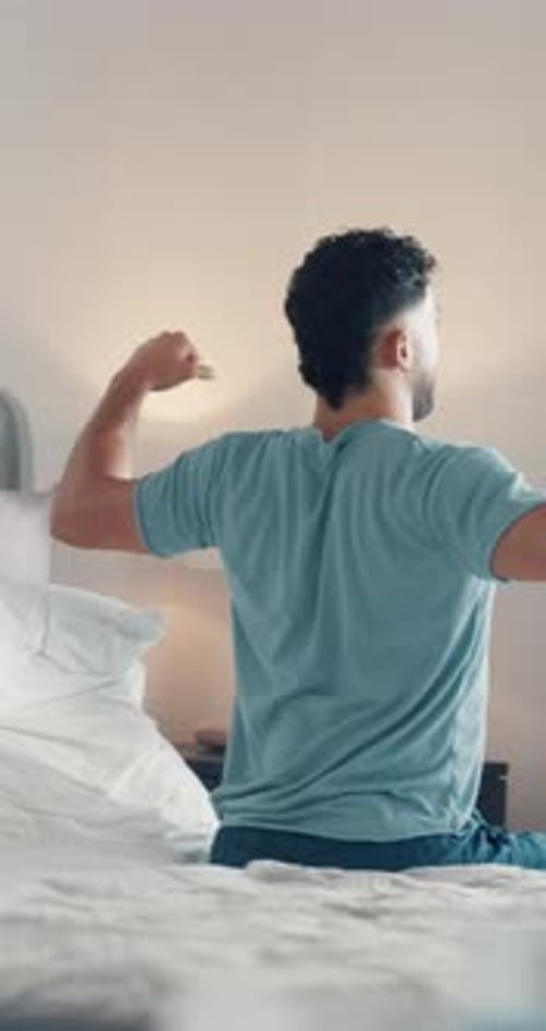 Young Man Stretching and Waking Up in Bed