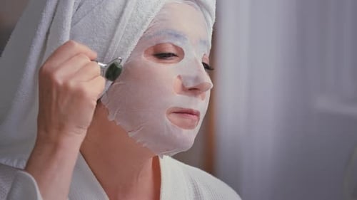 Caucasian Old Grandma Woman Senior Mature Lady in Bathroom with Towel on Head Doing Face Massage