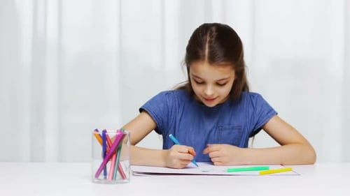 Child Draws Pictures with Markers at White Table