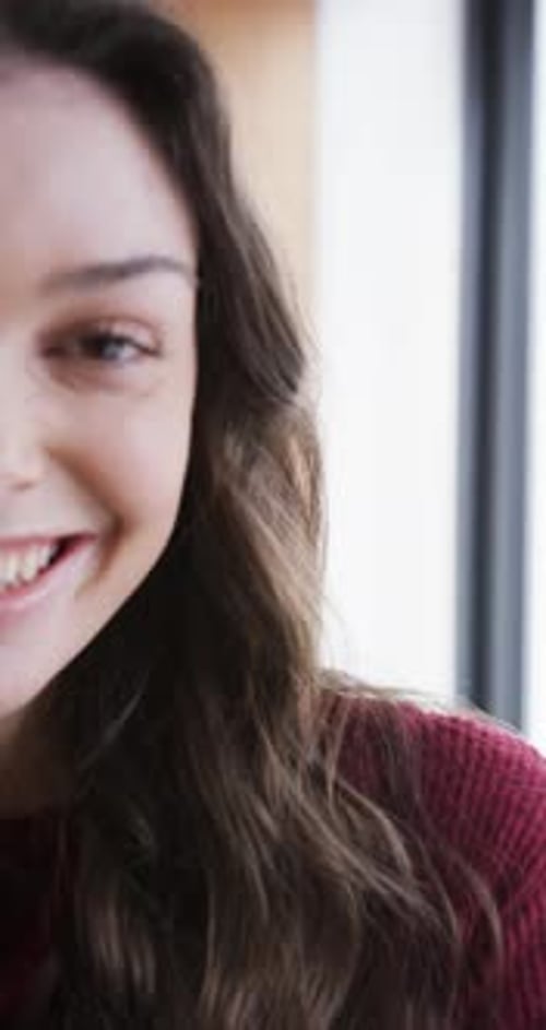 Demi-visage d'une femme caucasienne heureuse debout près de la fenêtre et souriante, Ralentissement
