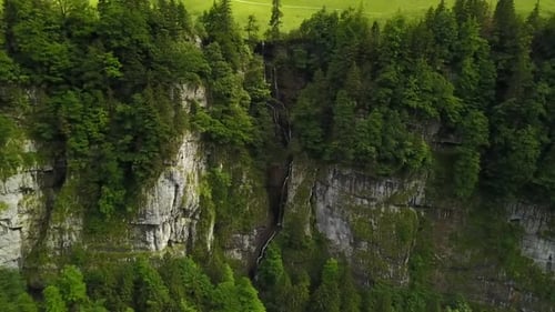 a flyaway from a waterfall with a small pan up revealing the mountain in the background