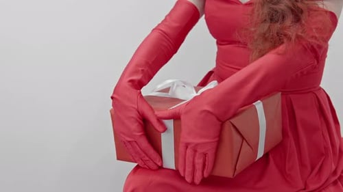 Woman in Red Dress Holding Gift Wrapped with Ribbon