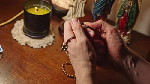 Hands Of Man Praying Rosary And Statues Of Jesus Mary And Angel