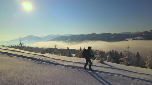 Aerial View of Backpacker Hiking Snowy Mountain Hillside on Cold Winter Day
