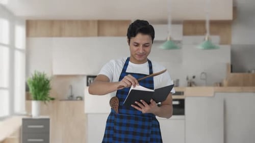 Young Adult Reading Recipe Book in Kitchen