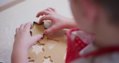 Close Up Of A Boy Cutting Out Christmas Cookies In Dough