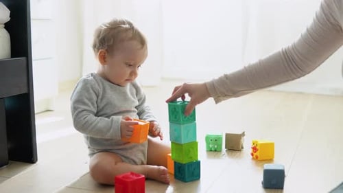 Criança brincando com blocos de brinquedos coloridos com a mãe