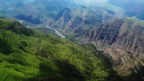 Lush Green Mountains with Terraced Fields a Winding River and Roads Under Clear Blue Skies