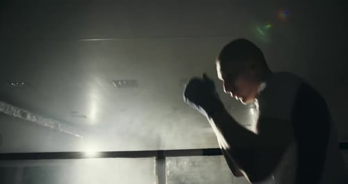 Night Training in the Hall of a Young Guy Professional Athlete in Boxing Training Punches in the