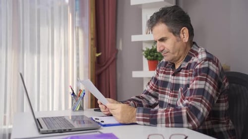 Man working in home office looking at documents and charts.