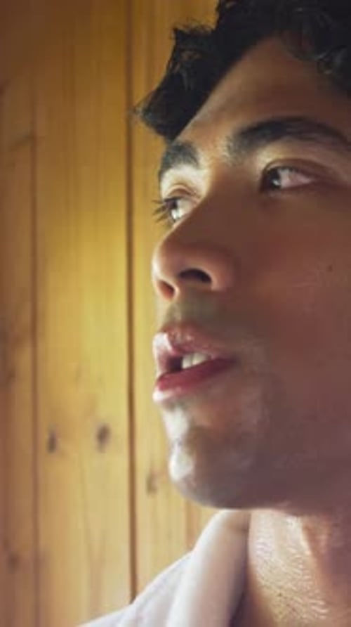 Vertical video: Opening eyes man turning head and breathing after sauna in wood-panel room, towel