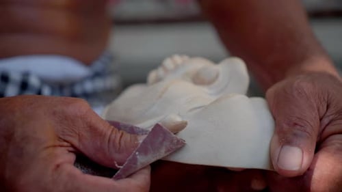 Traditional mask making process in Bali. Polishing the mask before applying the base and color.