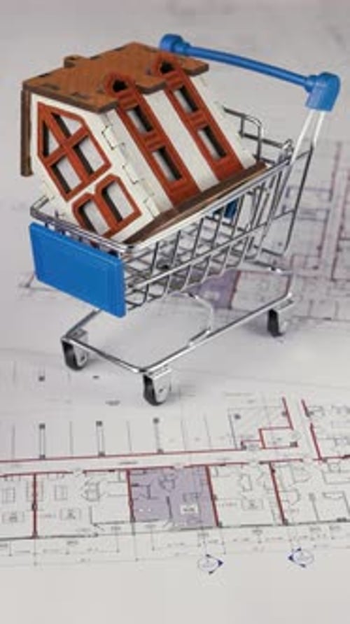 Miniature House in Shopping Cart on Blueprint