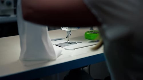 Close Up in the Sewing Workshop Young Girl Works with a Sewing Machine and White Fabric