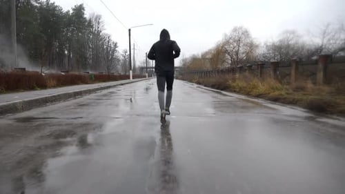 Strong Athlete in Sportswear Jogging Along Trail at Cloudy Day Young Sportsman Running Along Asphalt
