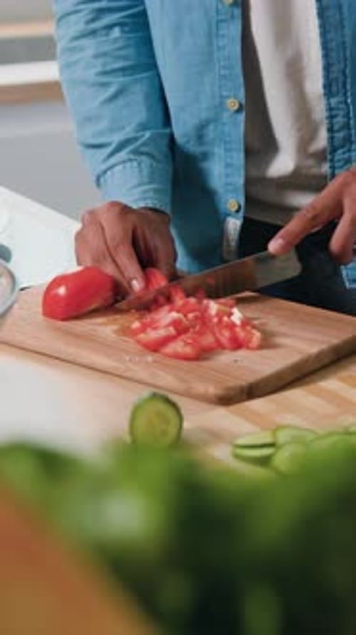 Adult Dicing Tomato on Wooden Board in Kitchen