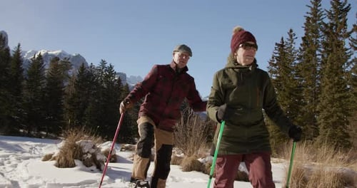 Senior Couple Snowshoeing Through Snowy Mountain Landscape