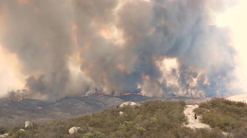 Des panaches de fumée emplissent le ciel alors que le photographe court vers un énorme feu incontrôlable
