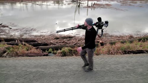 Man Walks on Path With Camera and Tripod