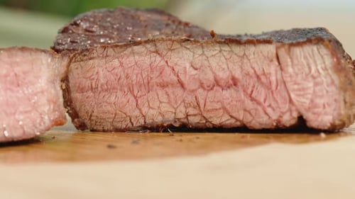 The slice of medium-rare beef steak on a wooden cutting board, close-up shot.