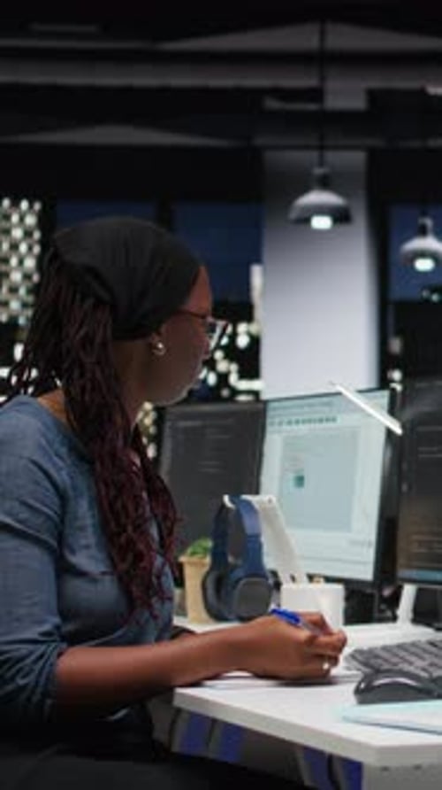 Vertikaler Videoprogrammierer macht sich Notizen am Schreibtisch im Firmenbüro im Silicon Valley