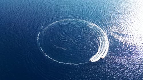 Motorboat leaving circular wake on blue water surface. Drone flying away. Croatia