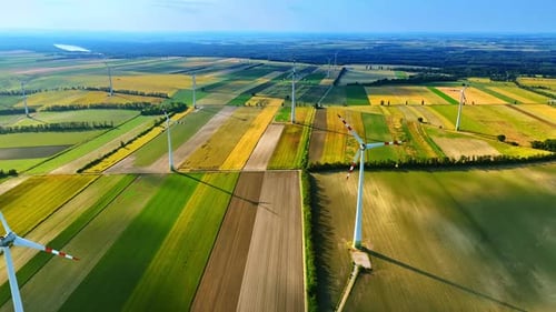 Windmills installed in the beautiful fields. Wind farms produce green energy. Aerial view.