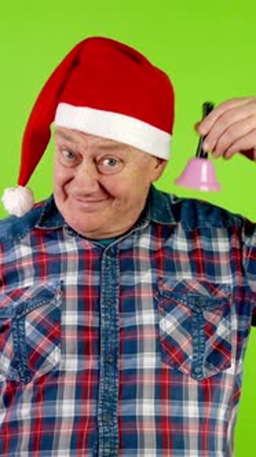Joyful Senior Man in Santa Hat Rings Christmas Jingle Bell and Laughs