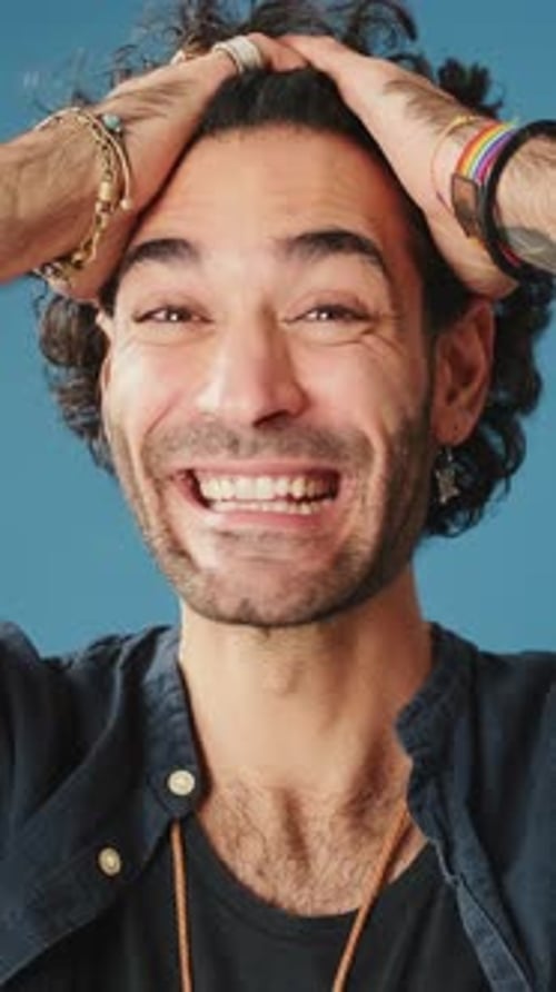 Close up, wonder man put his hands on head looking at camera isolated on blue background
