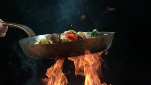 Pasta and Vegetables Tossing in Frying Pan over Fire