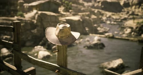 Cowboy Hat Resting on a Wooden Post Near a River in the Wilderness