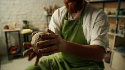 A potter works clay on a potter's wheel A potter forms a clay product using pottery tools