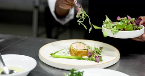 Chef Plating Salmon Dish with Greens and Asparagus