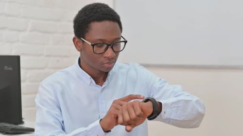 Man Checks his Smartwatch in Office Setting