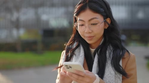 Smiling Woman Uses Smartphone in Urban Setting