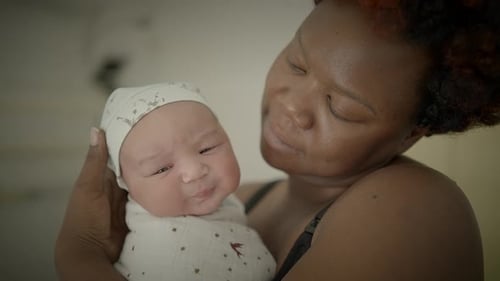 Loving Mother Holding Newborn Infant in Her Arms
